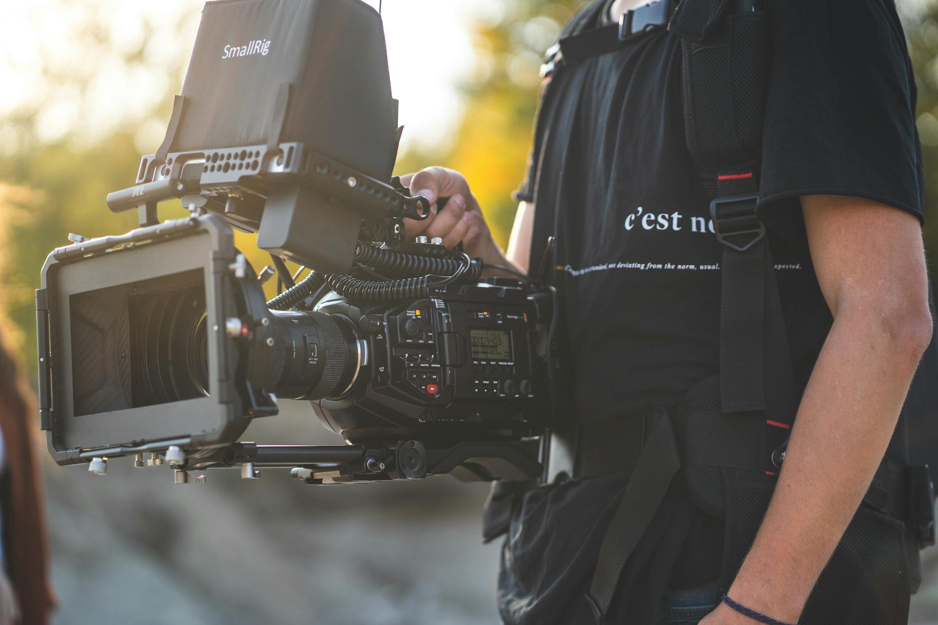 Close-up of a professional camera operator using a large camera rig outdoors.